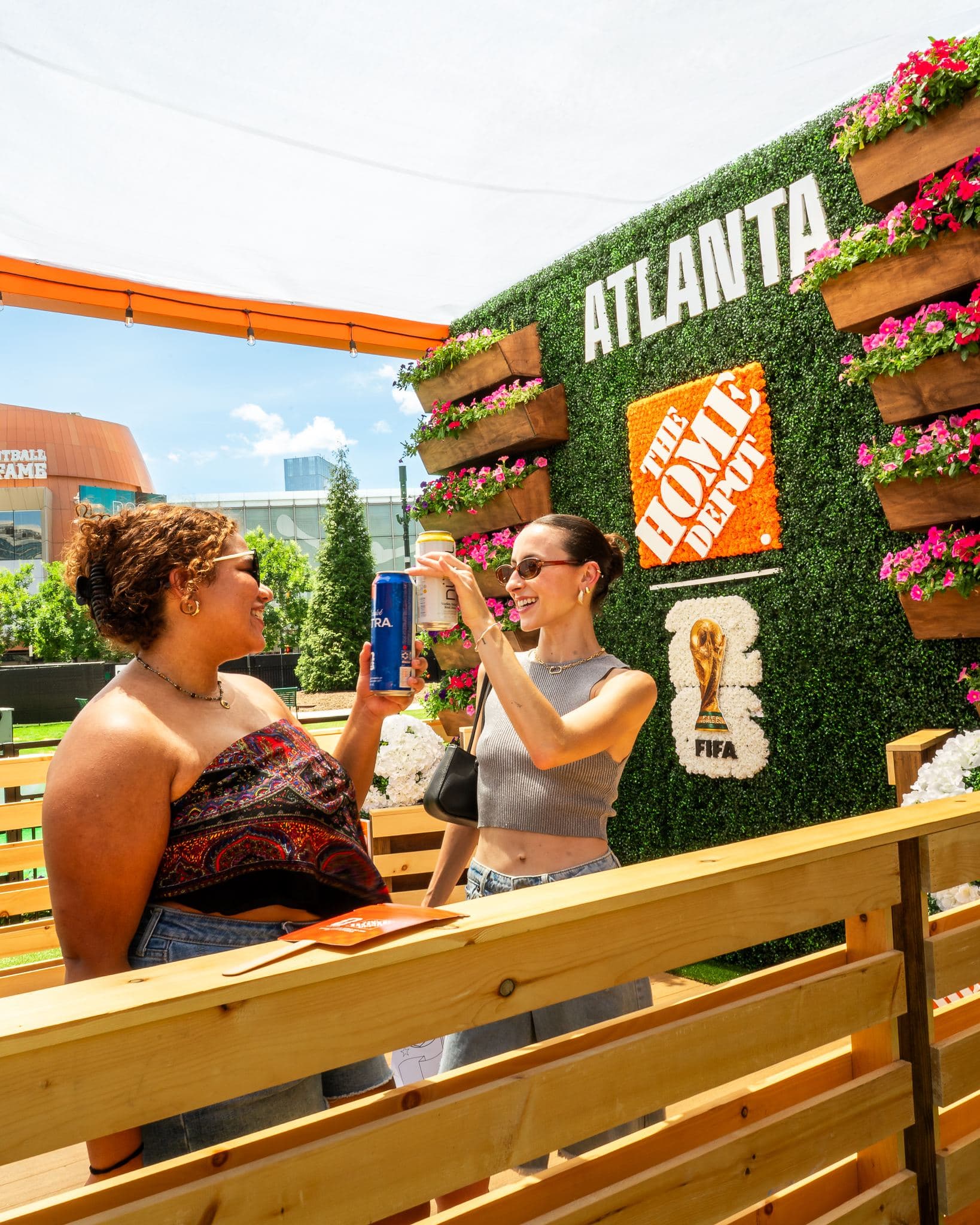 Two friends toasting in front of the Home Depot Atlanta flower wall at FIFA Fan Fest