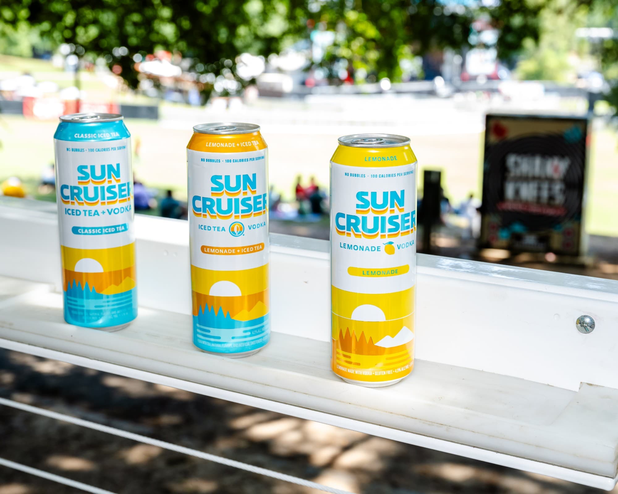 Sun Cruiser Classic Iced Tea, Lemonade and Iced Tea, and Lemonade vodka cans lined up on a railing overlooking Shaky Knees